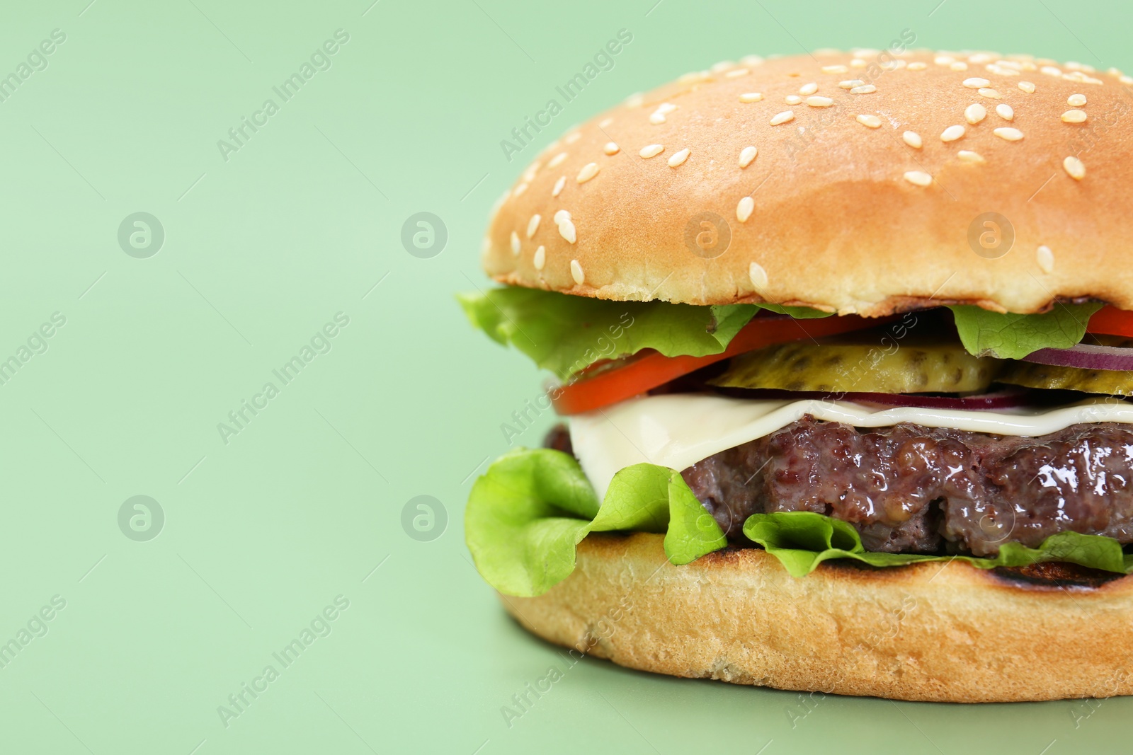 Photo of Burger with delicious patty on green background, closeup. Space for text