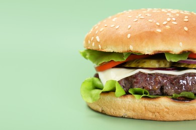 Burger with delicious patty on green background, closeup. Space for text