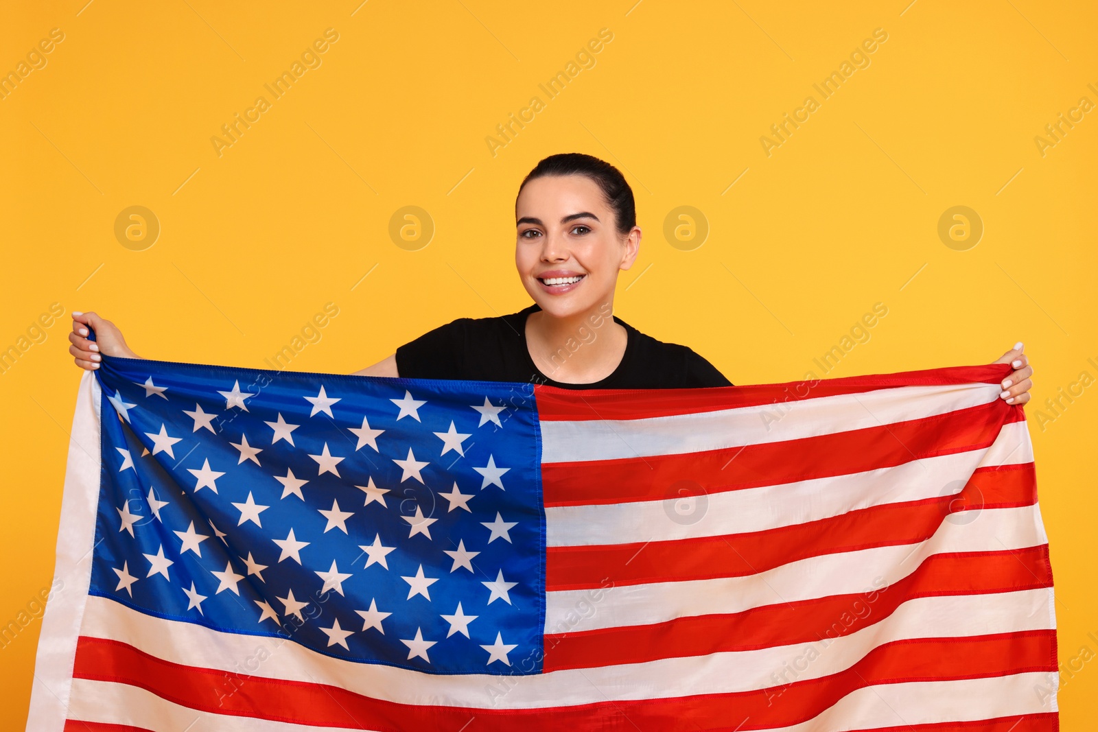 Photo of 4th of July - Independence Day of USA. Happy woman with American flag on yellow background