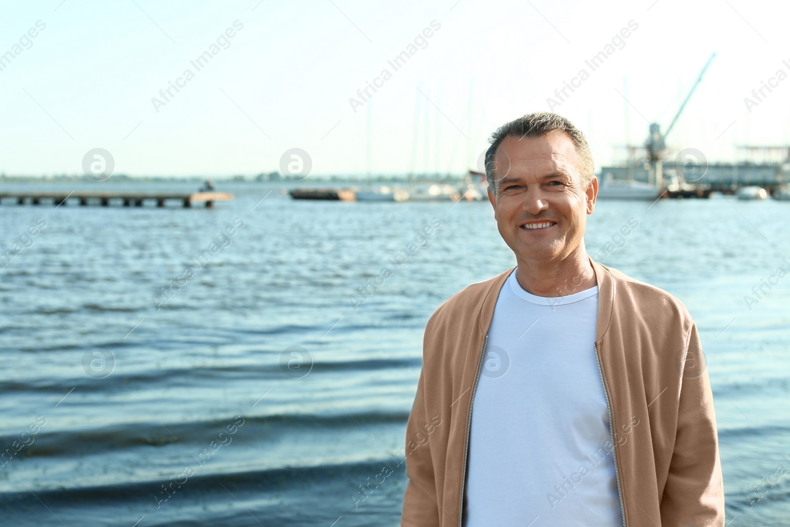 Photo of Male pensioner near river on sunny day. Space for text