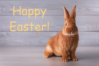 Happy Easter! Cute bunny on grey table against wooden background 