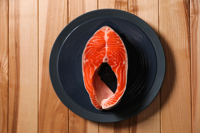 Fresh raw fish steak on wooden table, top view