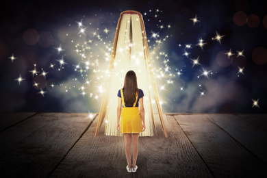 Image of Woman and book with magic glowing on wooden surface. Fairy tale