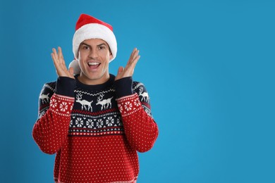 Photo of Excited man in Santa hat on blue background, space for text. Christmas countdown