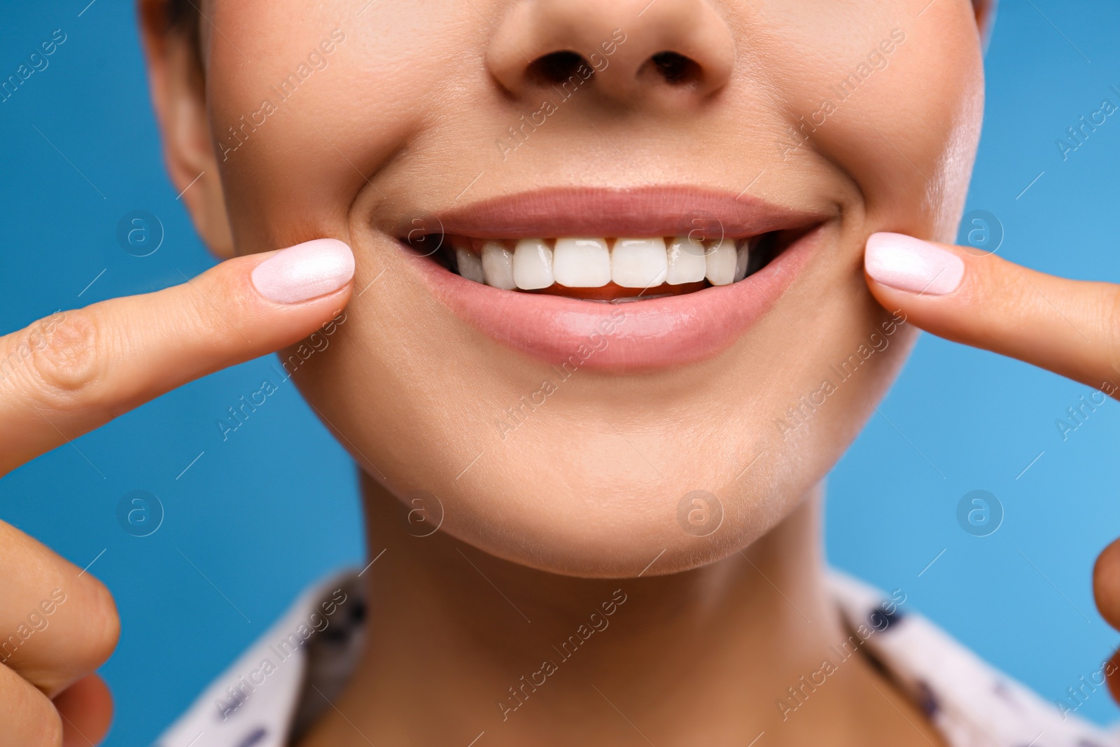 Photo of Young woman with beautiful smile on blue background, closeup. Cosmetic dentistry