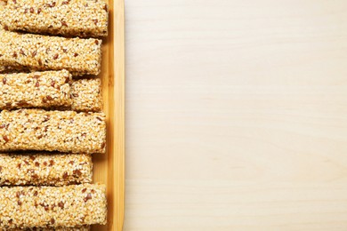 Plate with tasty sesame seed bars on wooden table, top view. Space for text