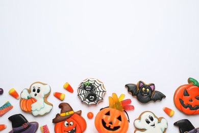 Photo of Tasty cookies and sweets for Halloween party on white table, flat lay. Space for text