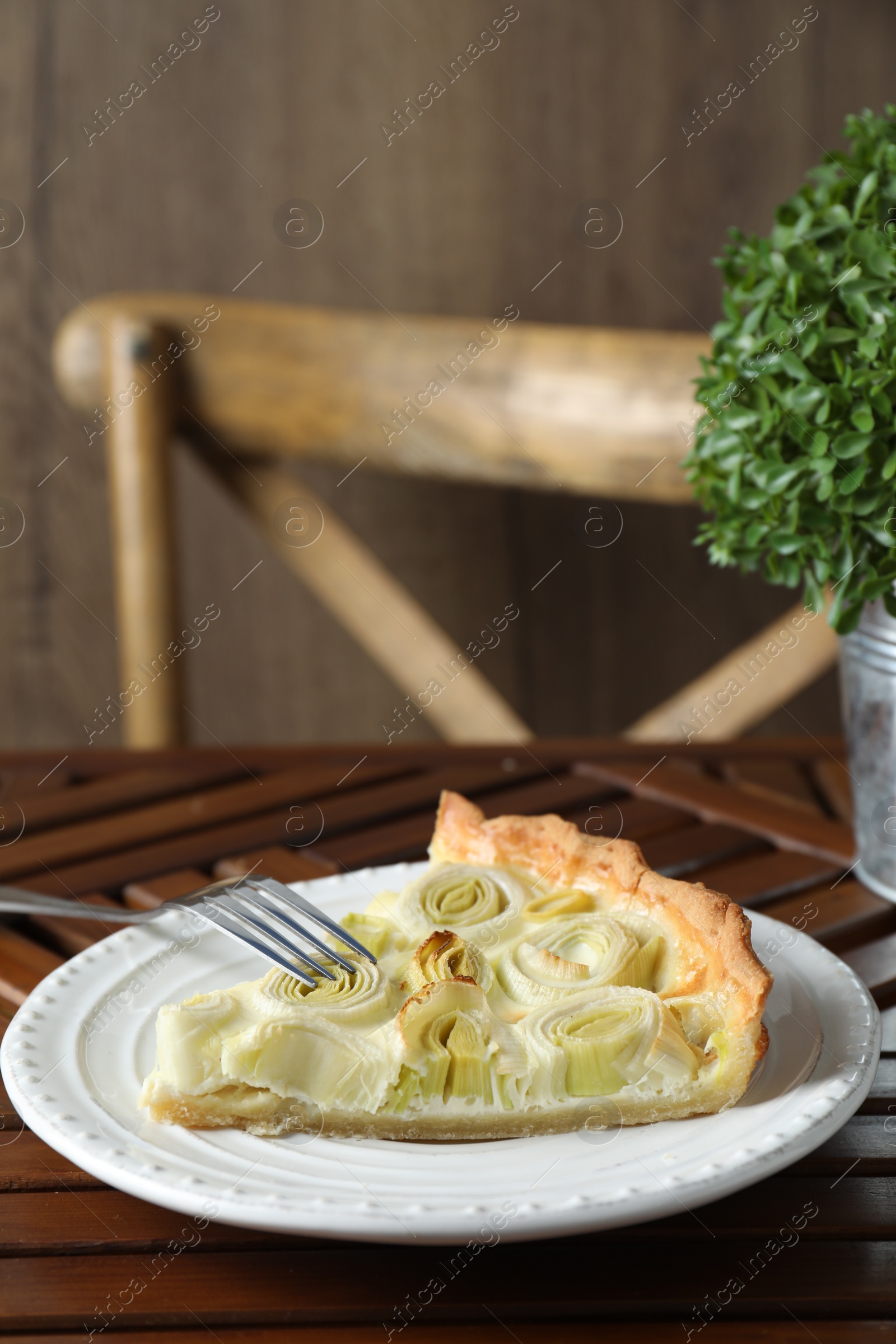 Photo of Plate with piece of tasty leek pie and fork on wooden table