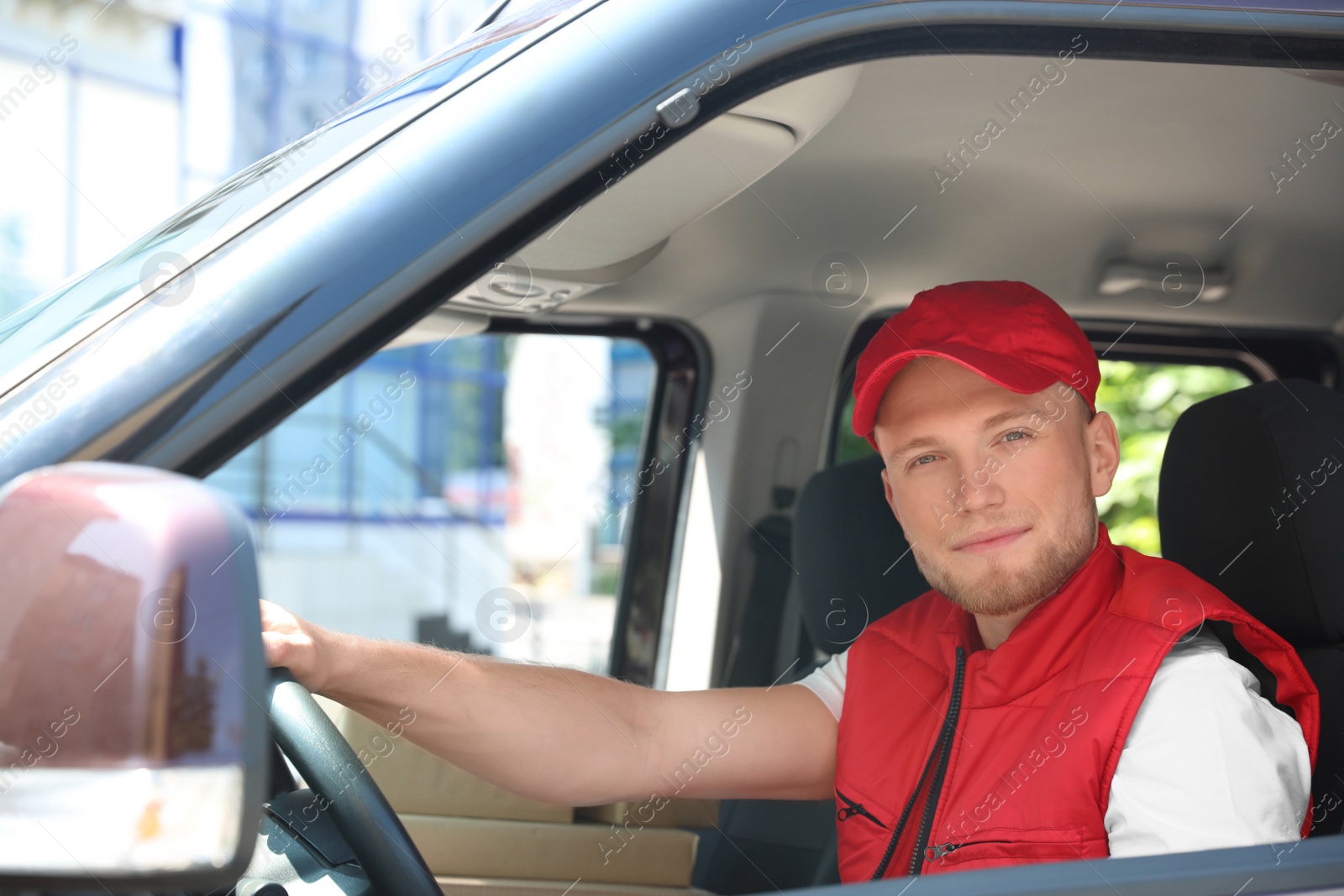 Photo of Young courier with parcels in delivery car