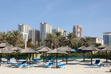 Photo of SHARJAH, UNITED ARAB EMIRATES - NOVEMBER 04, 2018: Sandy beach with umbrellas on sunny day