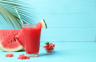 Photo of Summer watermelon drink in glass and sliced fruit on table against color background with space for text