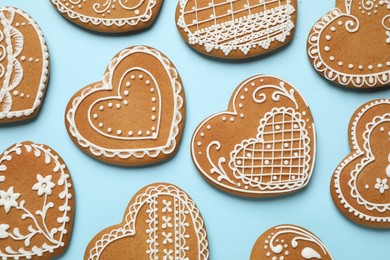 Photo of Tasty heart shaped gingerbread cookies on light blue background, flat lay