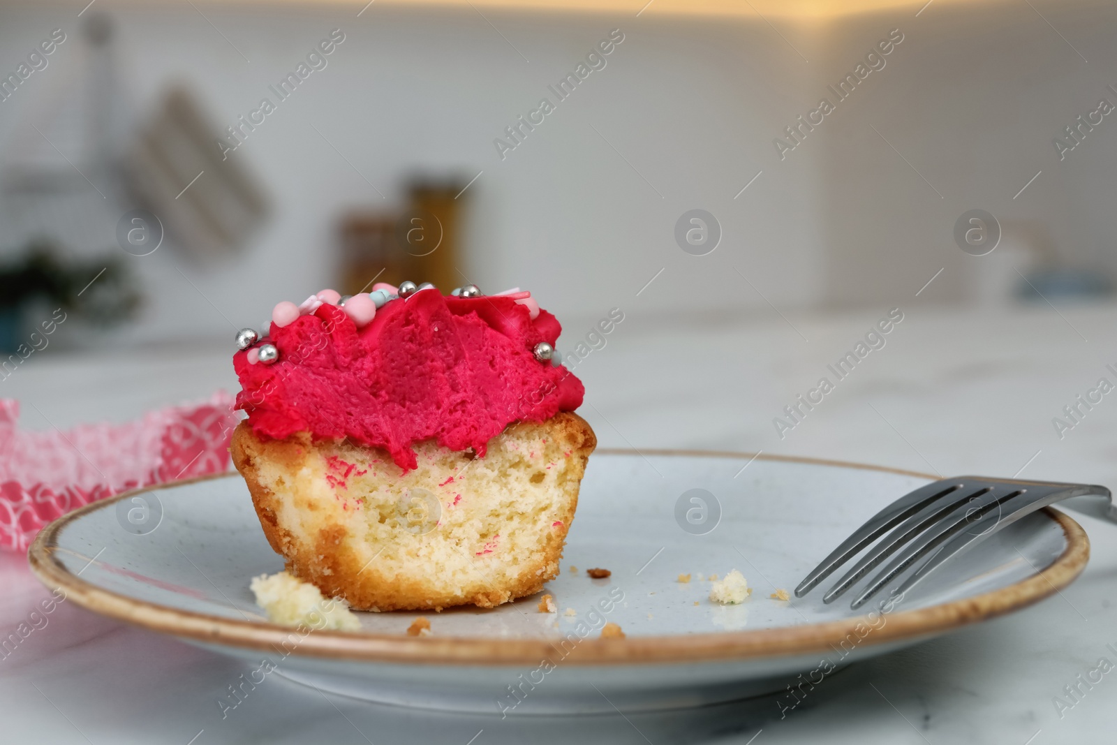 Photo of Bitten cupcake with cream on plate, closeup