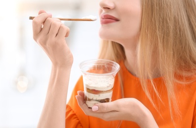 Young woman with yogurt on blurred background, closeup