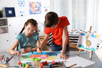 Photo of Little children painting picture at table indoors