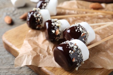 Photo of Delicious marshmallows covered with chocolate on board, closeup