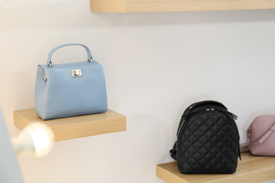 Photo of Stylish woman's bags on shelves in boutique