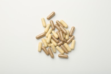 Different vitamin capsules on white background, top view