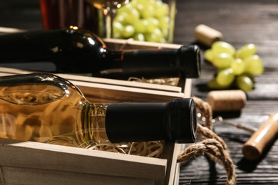 Photo of Wooden crates with bottles of wine on table, closeup