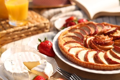 Photo of Strawberries, brie cheese and apple pie on blanket, closeup. Summer picnic