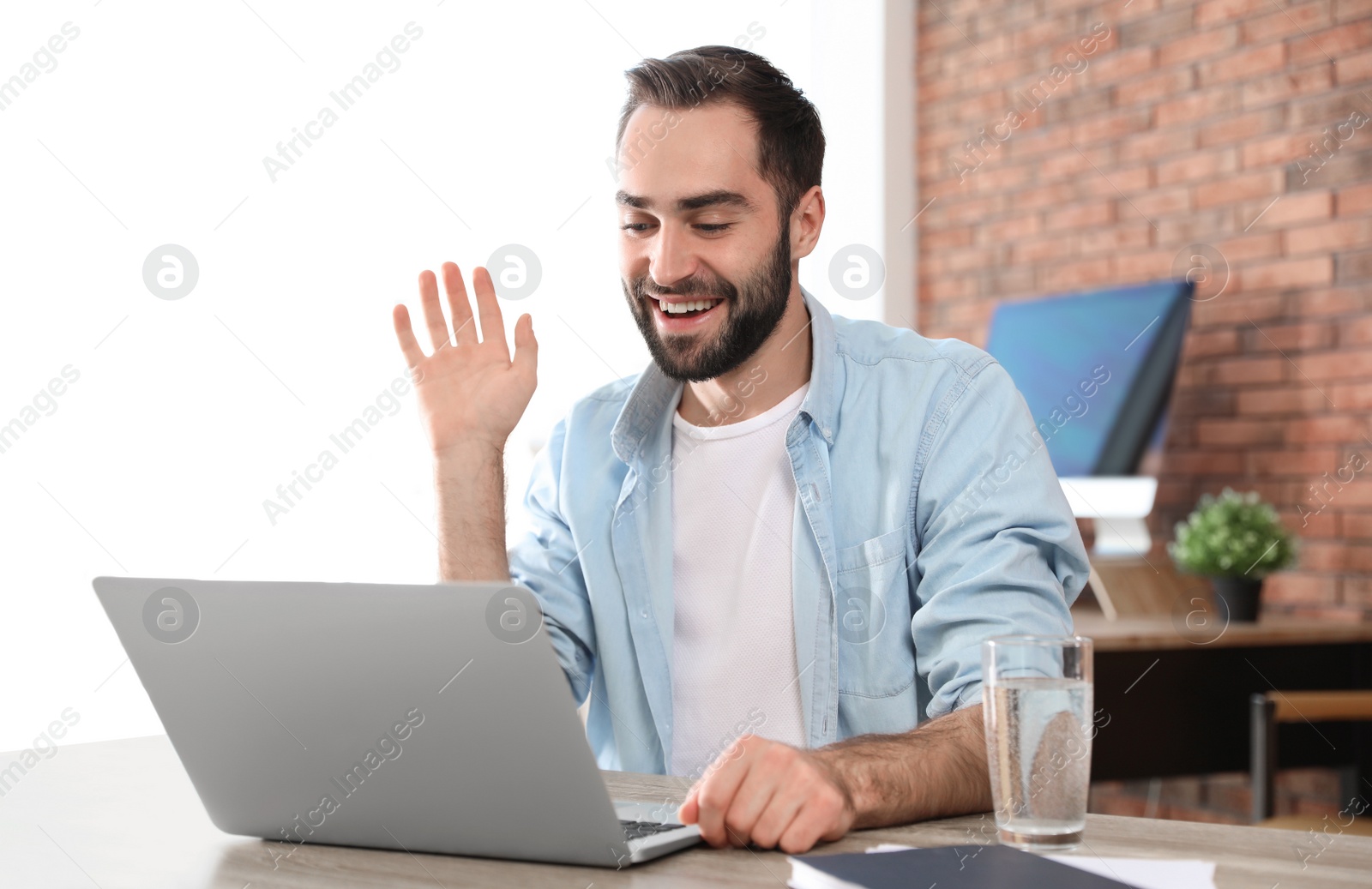 Photo of Young man using video chat on laptop in home office