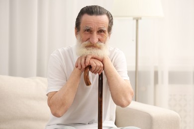 Photo of Senior man with walking cane on sofa at home