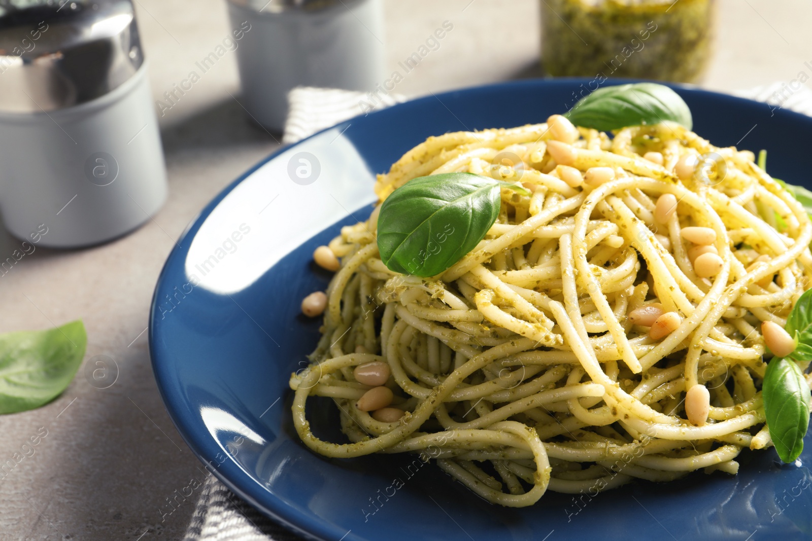 Photo of Plate of delicious basil pesto pasta on table, closeup