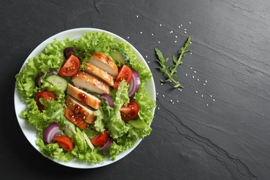 Photo of Delicious salad with chicken and vegetables on black table, top view. Space for text