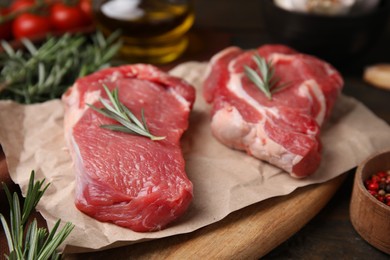 Photo of Fresh raw meat with rosemary on wooden table, closeup