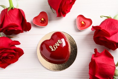 St. Valentine's Day. Delicious heart shaped cake, roses and candles on white wooden table, flat lay
