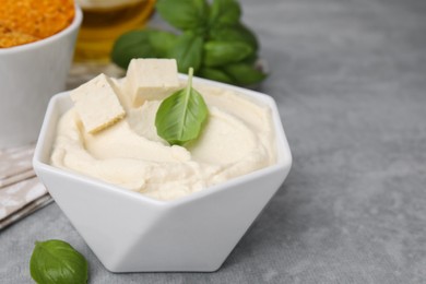 Photo of Delicious tofu sauce and basil leaves on grey table, closeup. Space for text