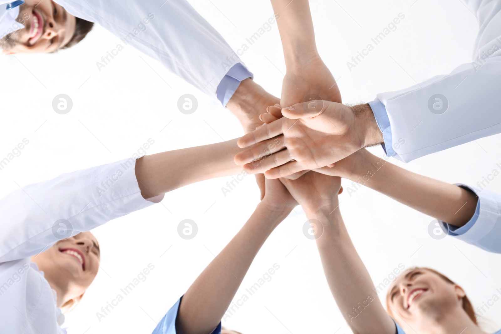 Photo of Team of medical doctors putting hands together on white background, closeup. Unity concept