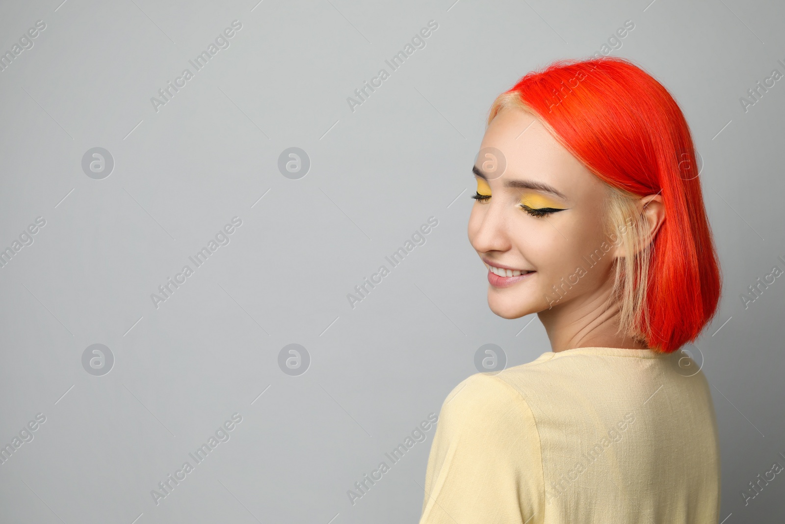 Photo of Beautiful young woman with bright dyed hair on light grey background, space for text