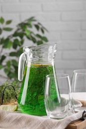 Photo of Jug of homemade refreshing tarragon drink and glasses on table