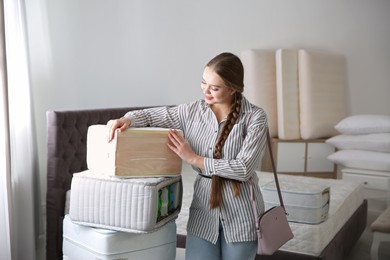 Young woman choosing mattress in furniture store
