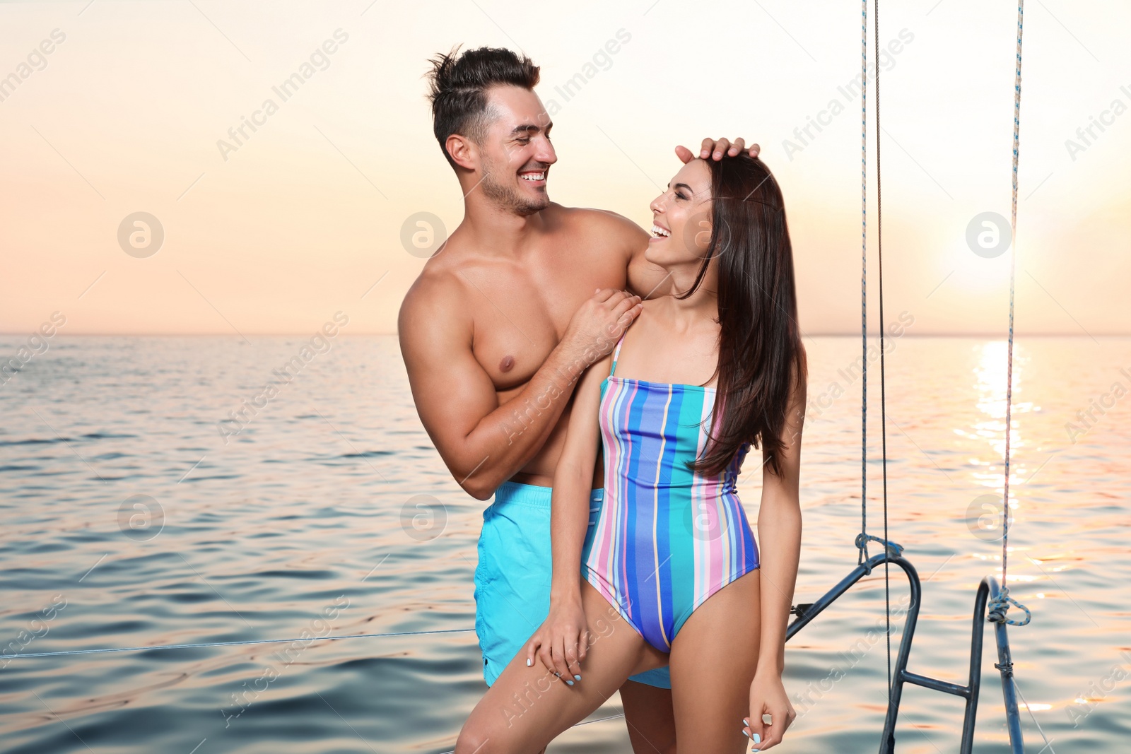 Photo of Young man and his beautiful girlfriend in bikini on yacht. Happy couple during sea trip