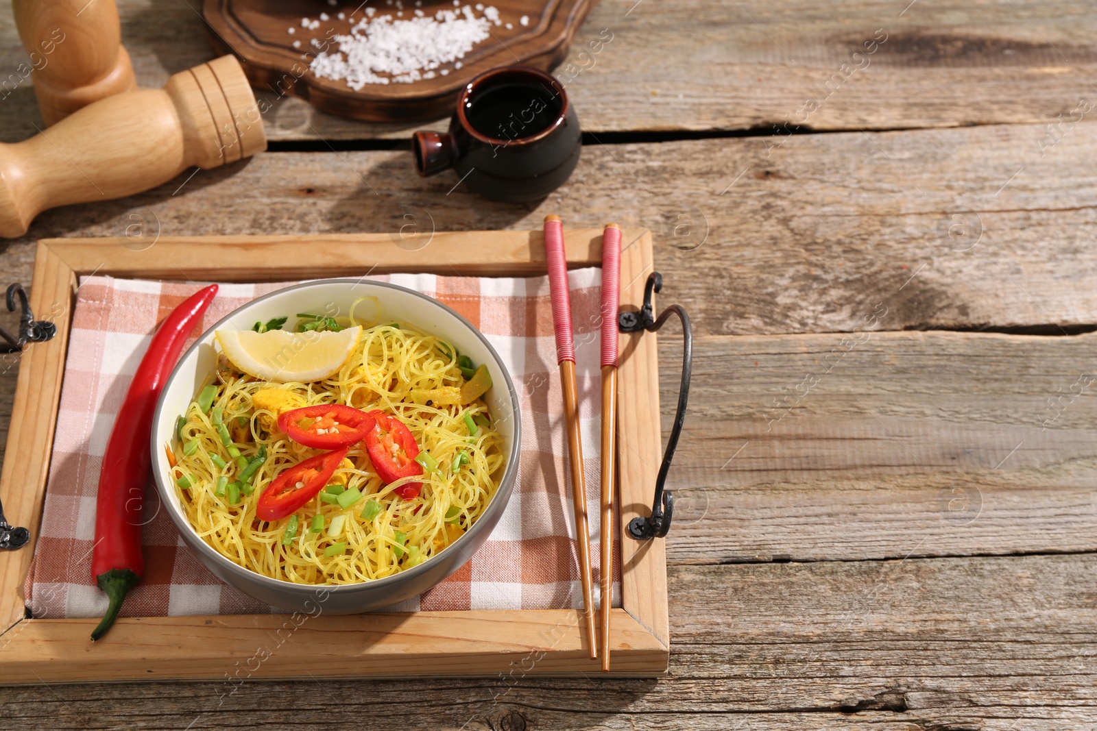 Photo of Stir-fry. Tasty noodles with vegetables and meat in bowl served on wooden table, flat lay. Space for text