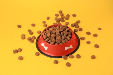 Dry dog food and feeding bowl on orange background