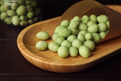Photo of Tasty wasabi coated peanuts on wooden table, closeup