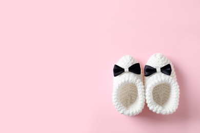 Handmade baby booties on color background, top view with space for text