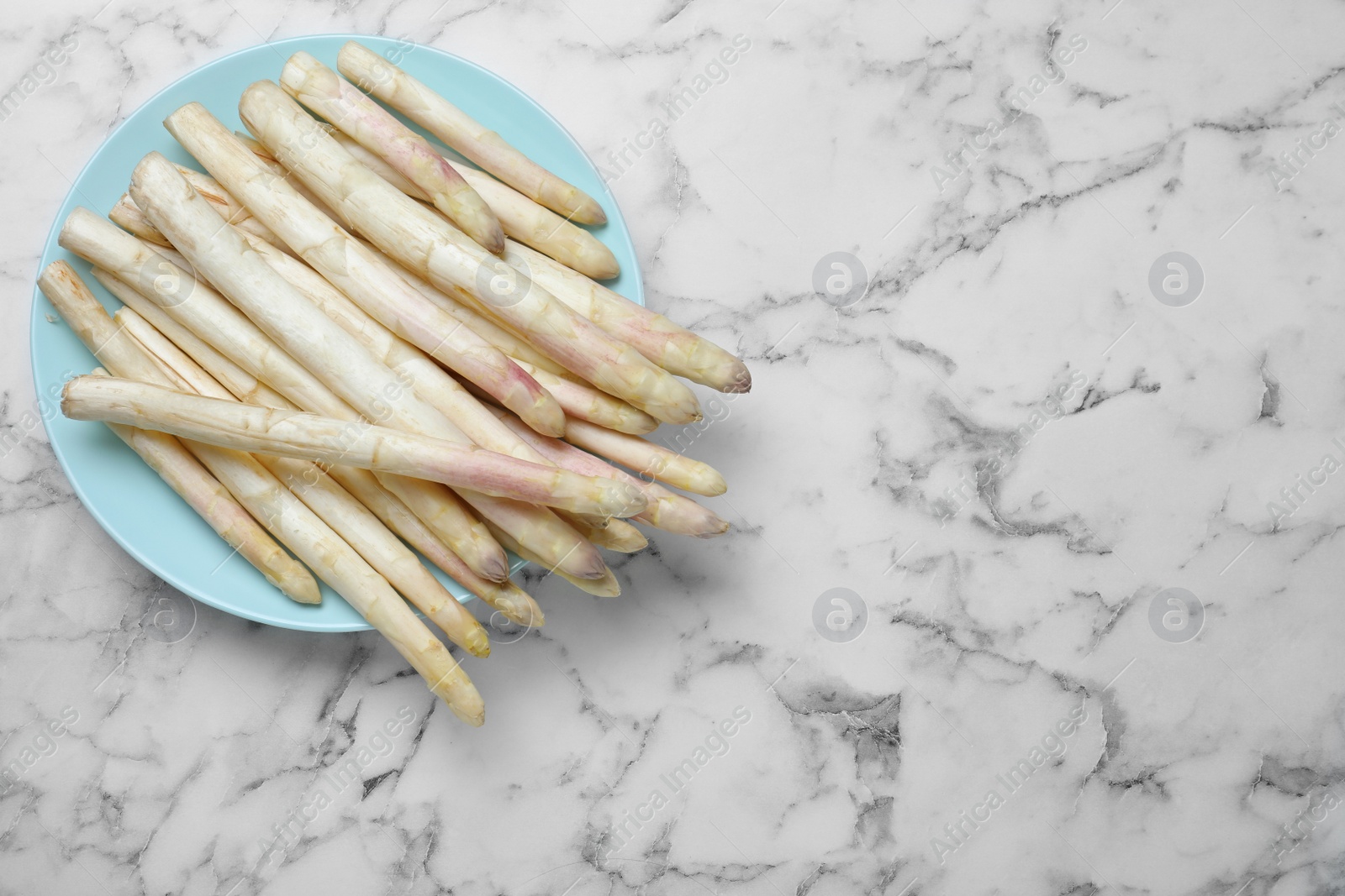 Photo of Fresh white asparagus on marble table, top view. Space for text