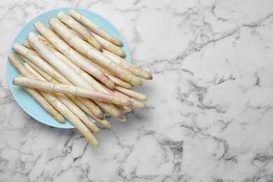 Photo of Fresh white asparagus on marble table, top view. Space for text