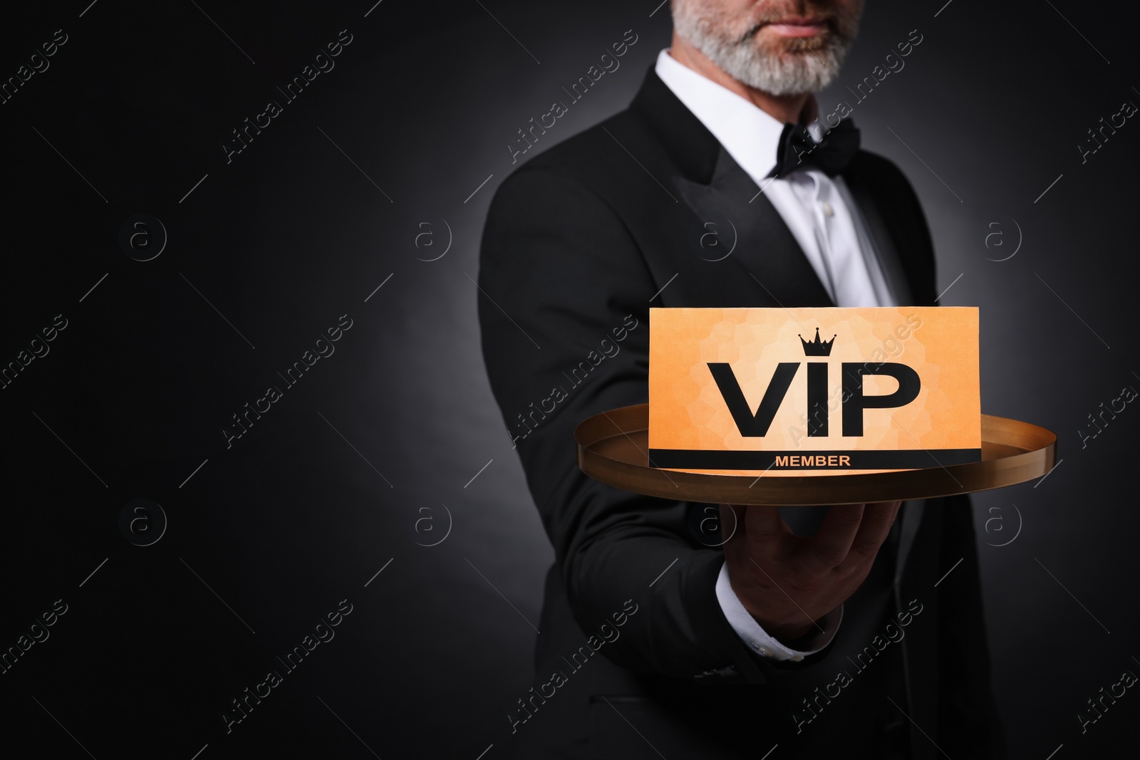 Photo of Man holding tray with VIP sign on black background, closeup. Space for text