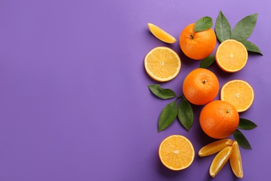 Delicious oranges on purple background, flat lay. Space for text