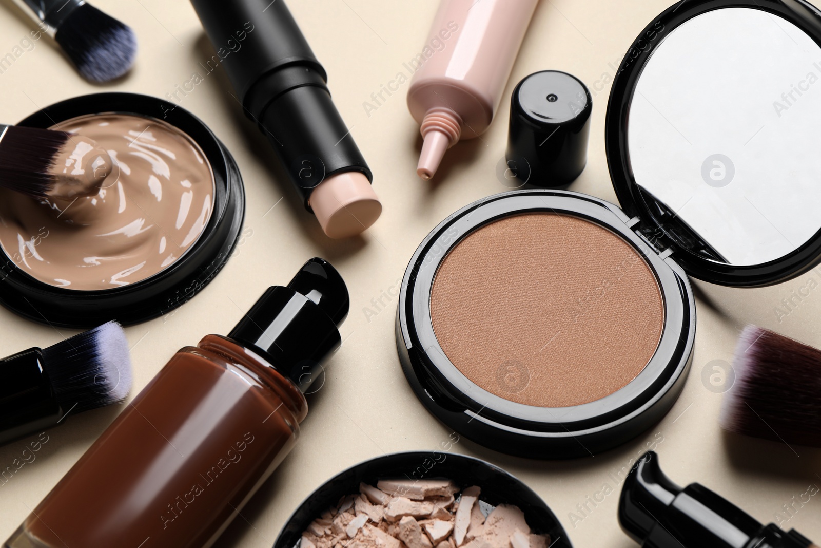 Photo of Liquid foundations, beauty accessories and face powders on beige background, closeup