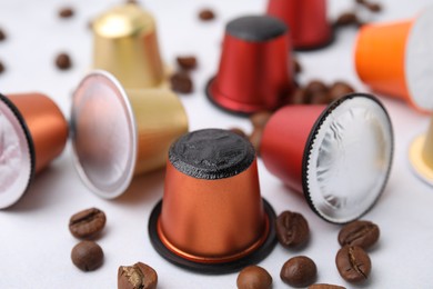 Photo of Many coffee capsules and beans on white table, closeup