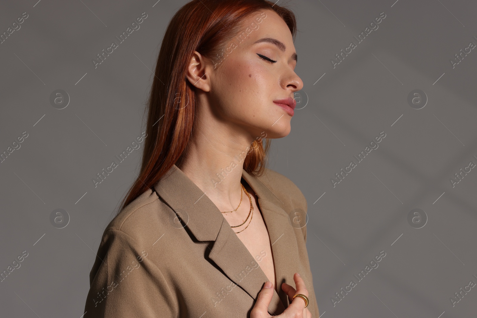 Photo of Beautiful young woman with elegant jewelry on gray background