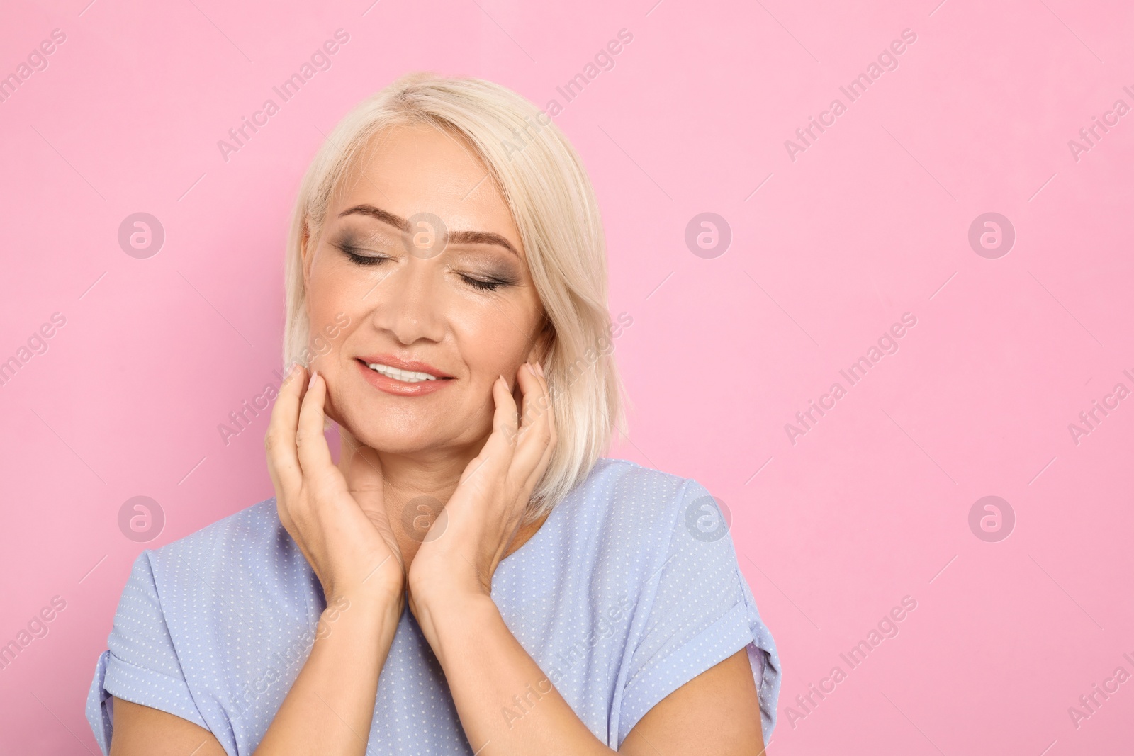 Photo of Portrait of mature woman with beautiful face on pink background. Space for text