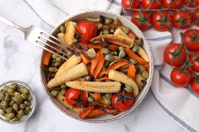 Tasty roasted baby corn with tomatoes and capers on white marble table, flat lay