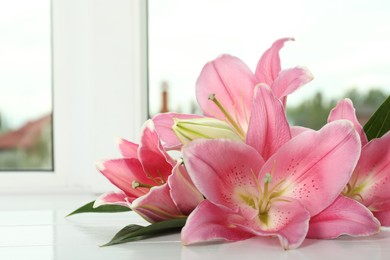 Photo of Beautiful pink lily flowers on window sill indoors